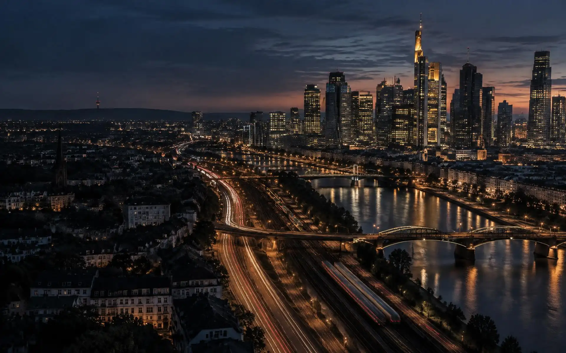 A European business district at dusk, with motorways, rail lines and river bridges linking the city